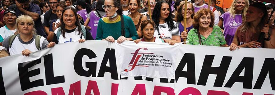 En el marco del Paro convocado por la CGT, la Federación de Profesionales del GCABA junto a otras organizaciones de salud que participan del Cabildo abierto, marchan contra la Reforma laboral 19/02/2026. En la foto: Andrea Ramírez, Rosa Favre y Natalia Castrogiovanni, integrantes del Consejo Ejecutivo,marchando junto a otras/os compañeros/as de la Federación de Profesionales del GCABA. Créditos: Antú Divito Trejo para FPSalud.