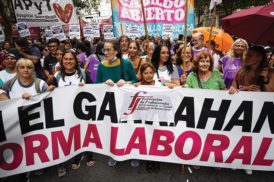 En el marco del Paro convocado por la CGT, la Federación de Profesionales del GCABA junto a otras organizaciones de salud que participan del Cabildo abierto, marchan contra la Reforma laboral 19/02/2026. En la foto: Andrea Ramírez, Rosa Favre y Natalia Castrogiovanni, integrantes del Consejo Ejecutivo,marchando junto a otras/os compañeros/as de la Federación de Profesionales del GCABA. Créditos: Antú Divito Trejo para FPSalud.
