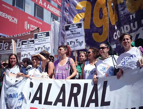 Compañeras de distintas asociaciones (ALE, AMdeBA, APSS, ATOGBA, APACSA, ADOM), llevando la bandera de la Federación de Profesionales del GCABA, en la movilización a Plaza de Mayo contra la Reforma Laboral, 18/12/2025. 